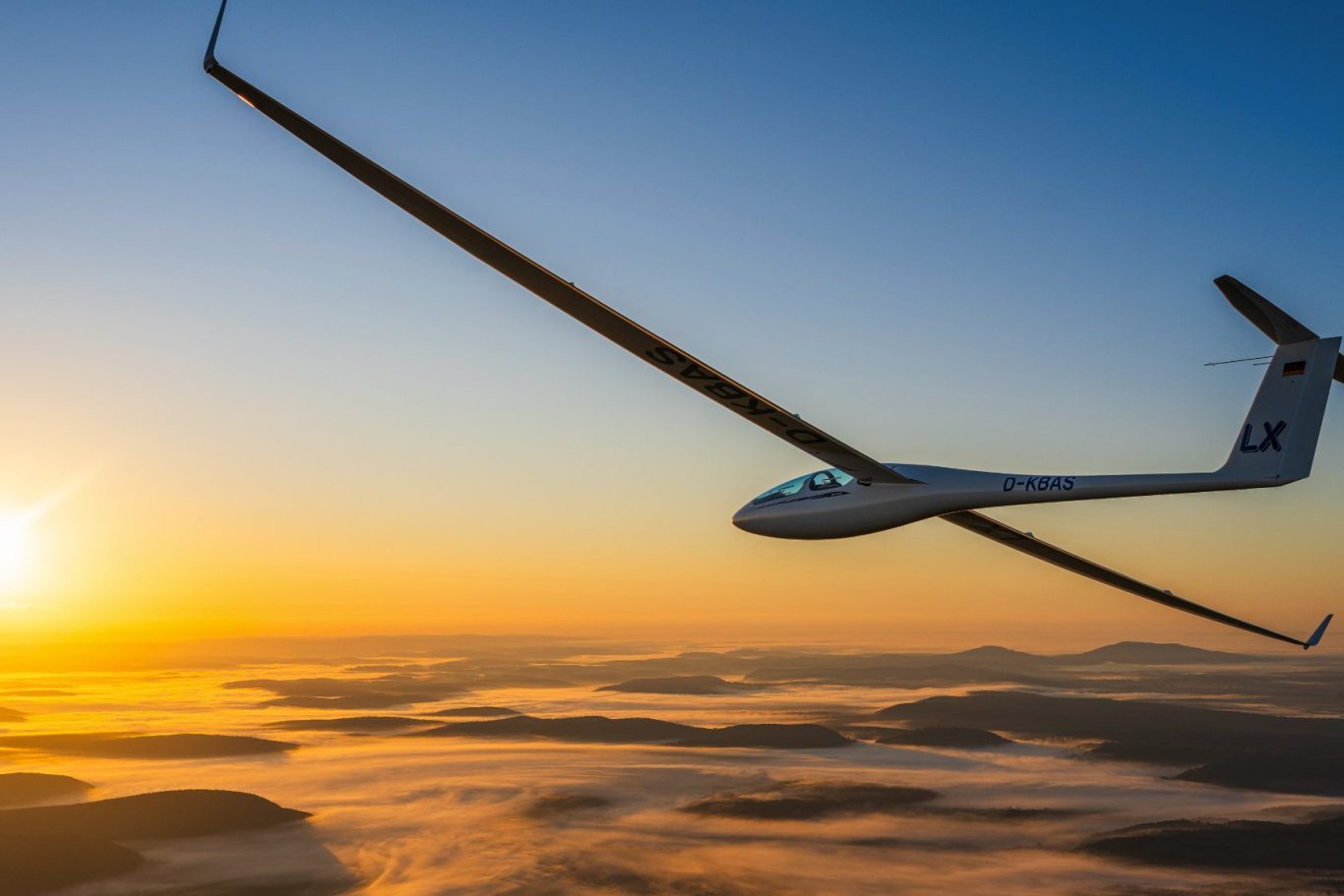 Luftbild einer ASG 32 im Sonnenaufgang über nebligen Landschaft Segelflugzeug fliegt hoch über einer nebligen Landschaft bei Sonnenaufgang.