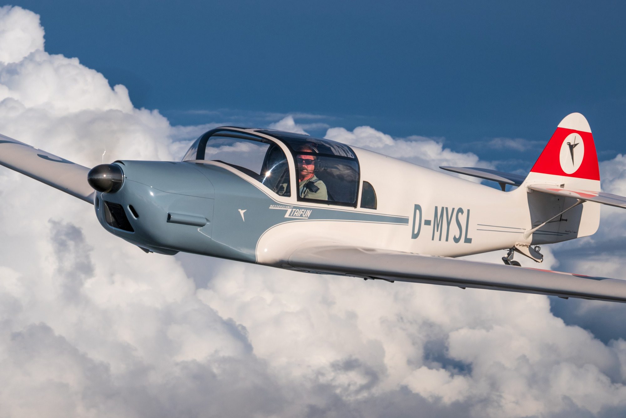 Me 108 fliegt über weißen Wolken mit einem Piloten im Cockpit.