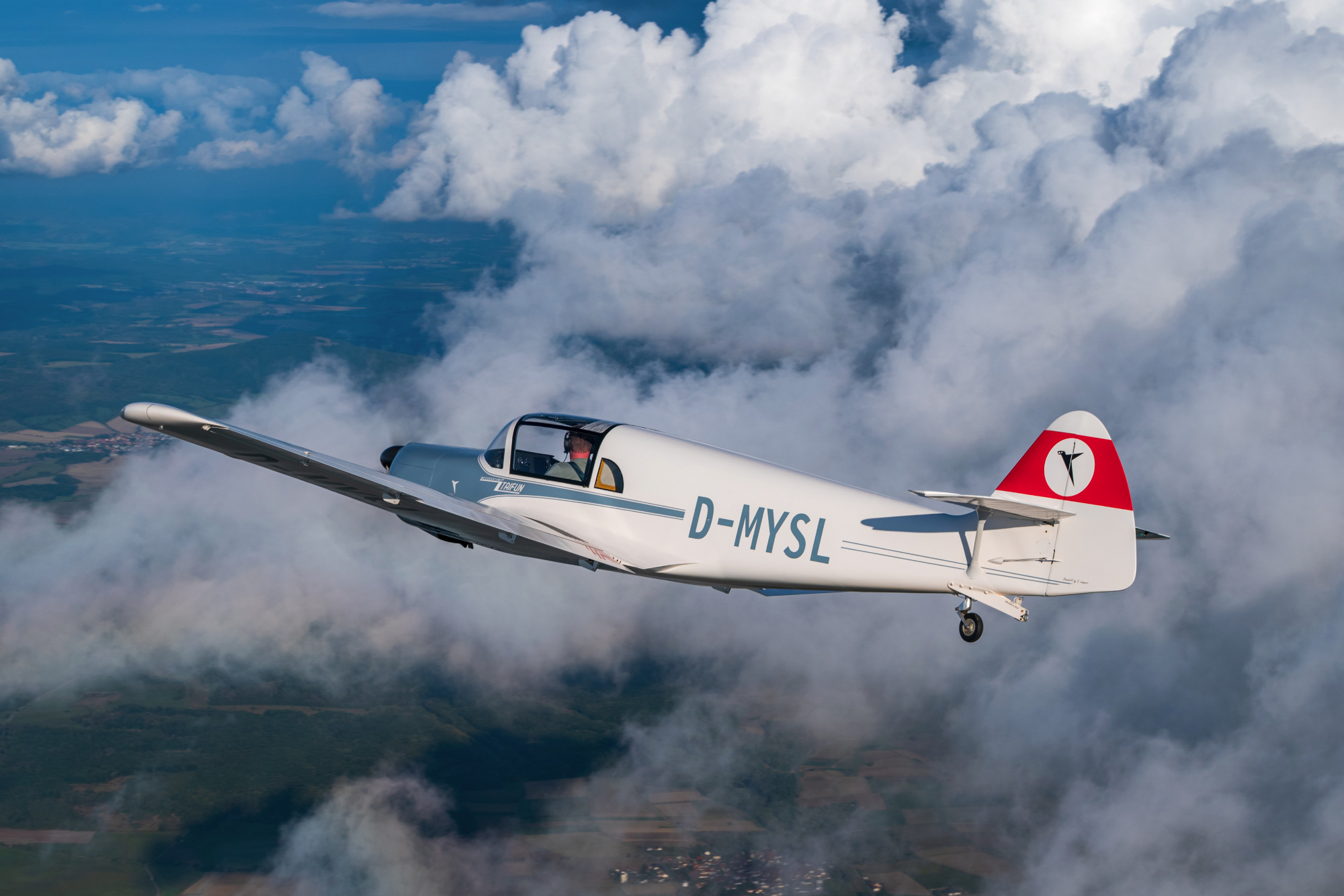 Ein Flugzeug mit rotem und weißem Design schwebt über den Wolken.
